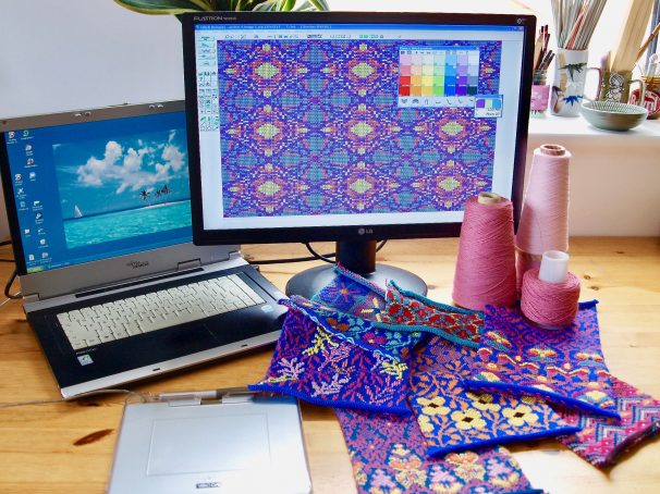 A computer screen showing the Designaknit software & 4 colour jacquard fabric swatches that have been knitted using the software. On the table there are also cones of yarn & a graphics tablet.
