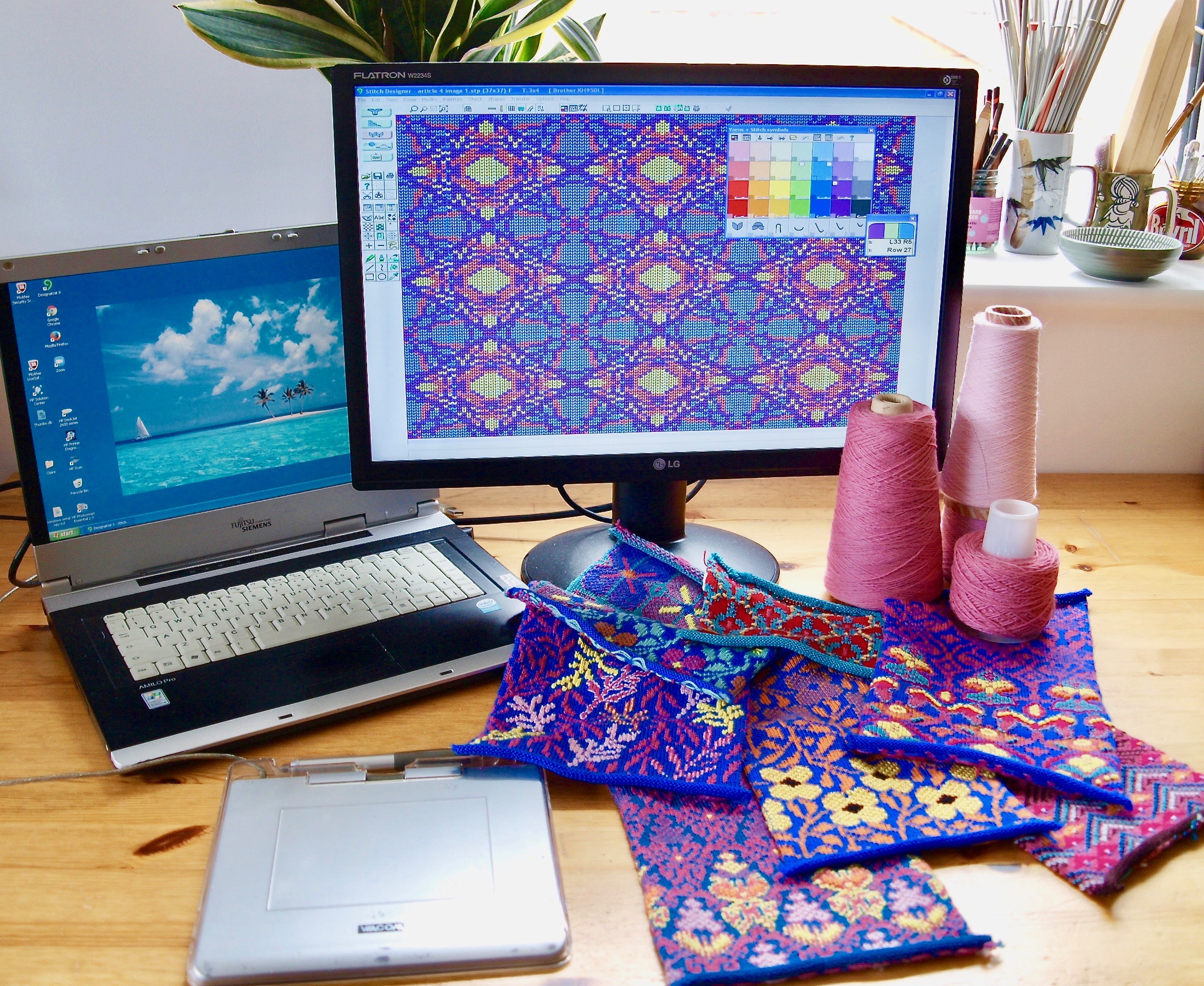 A computer screen showing the Designaknit software & 4 colour jacquard fabric swatches that have been knitted using the software. On the table there are also cones of yarn & a graphics tablet.