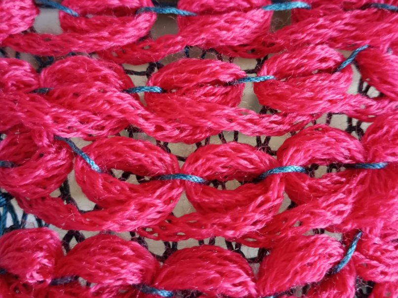 Machine knitted fabric showing wrapped stitches in bright pink knitted on a brother KH230 knitting machine