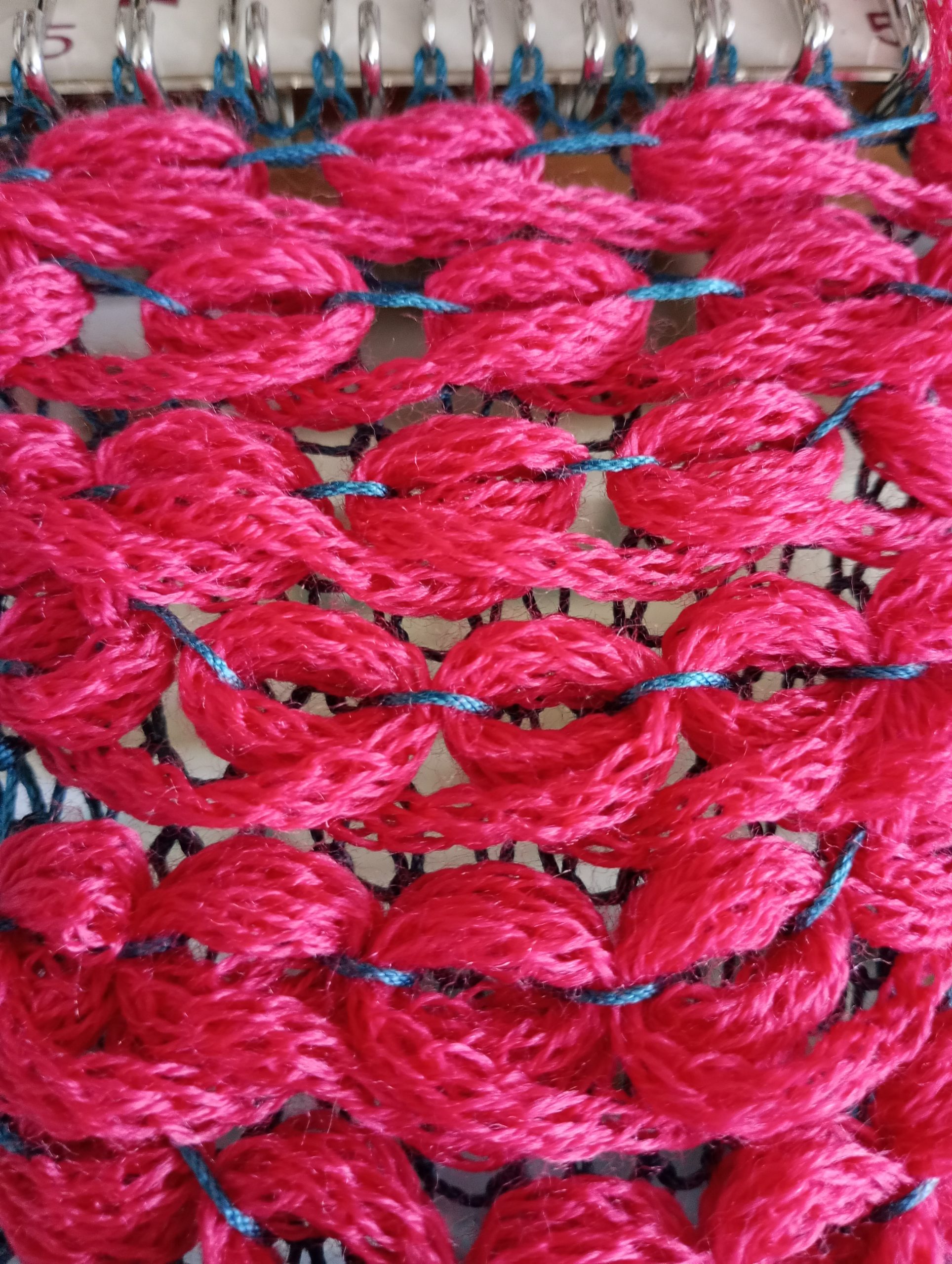 pink cord knitting wrapped yarn on big large scale knitting machine.